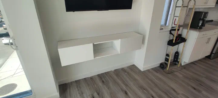 White floating media console assembled and mounted below a television